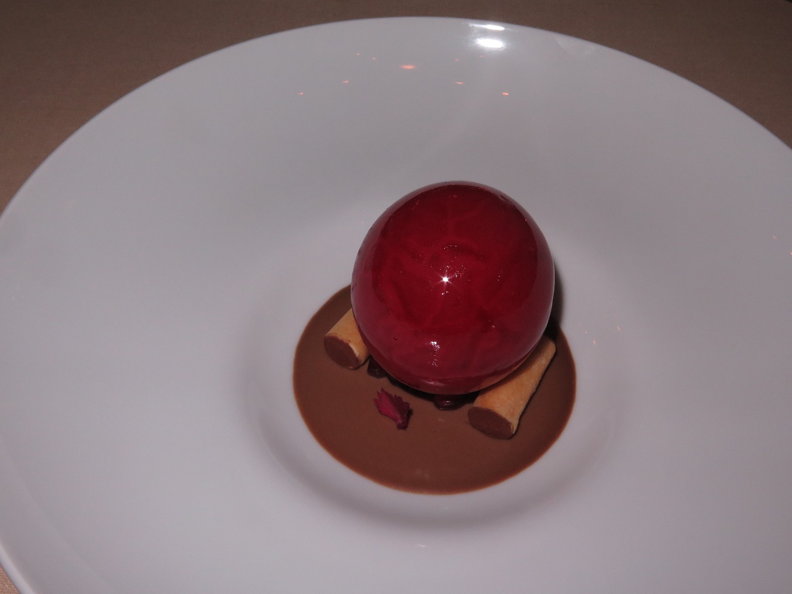Iced sphere of pomegranate on gianduia cream and cannelloni filled with salty pine-seed chantilly 