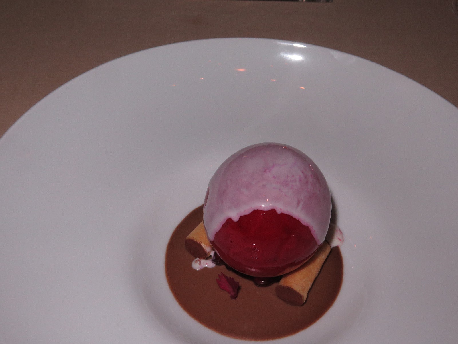 Iced sphere of pomegranate on gianduia cream and cannelloni filled with salty pine-seed chantilly 